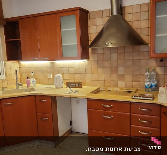מטבח עם ארונות עץ, כיור וברז, קומקום חשמלי